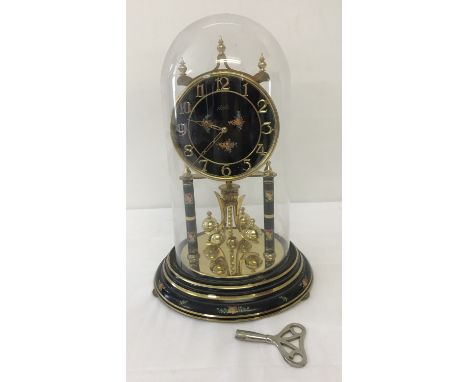  A vintage Kundo glass domed anniversary torsion ball pendulum clock.  In black with brass trim and flower design, complete w