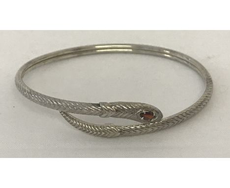 A silver bangle in the shape of a snake set with an oval cut garnet to the top of its head.  925 mark to inside. 