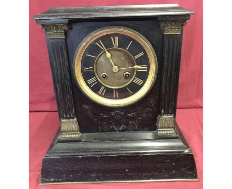 A large vintage heavy slate mantel clock with column detail to front.  Trimmed with brass detail and with Roman Numeral chara