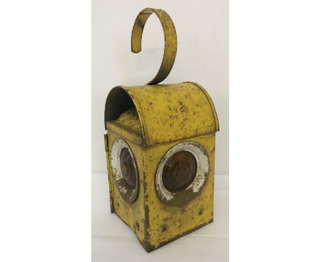 A vintage metal railway lamp with orange glass lenses and carrying hook, painted yellow.   Approx. 37cm tall.
