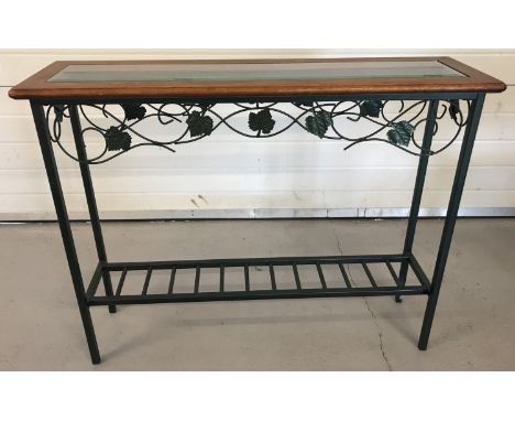 A modern wrought iron hall table with wooden top and bevel edged glass insert.  Base painted green with scroll and leaf desig