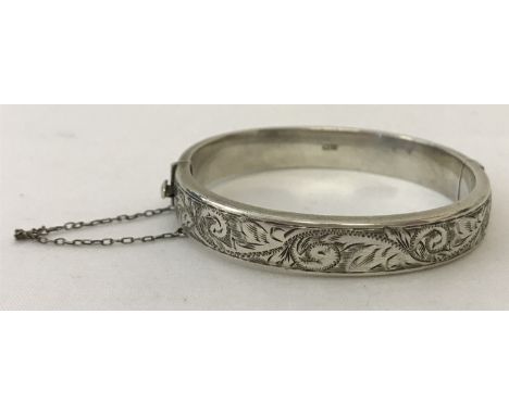 A vintage silver hinged bangle with engraved detail to one half.  Complete with safety chain. Hallmarked Birmingham 1962. 