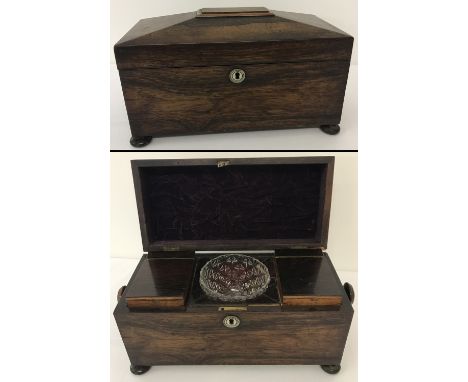 A mahogany coffin shaped, lined tea caddy on bun feet with mother of pearl lock surround.  With Turned finial handles to ends