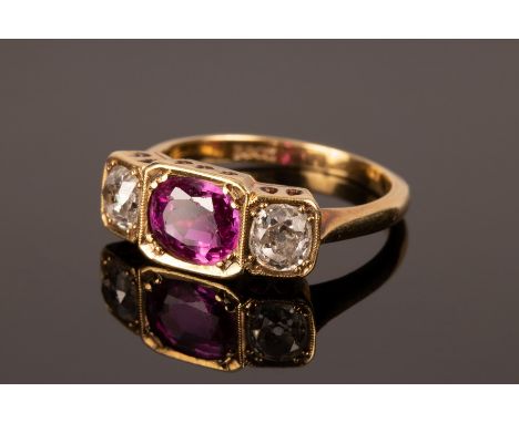 A ruby and diamond three-stone ring, set in 18ct yellow gold, the oval ruby measuring approximately 7mm x 6mm x 3.6mm, the di