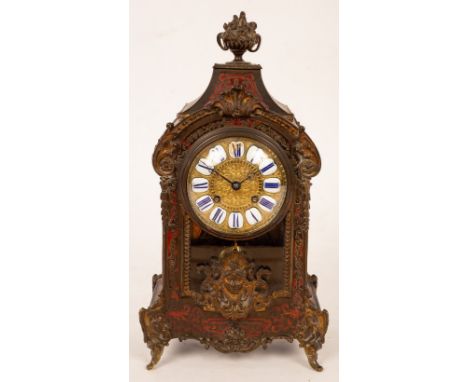 A 19th Century French mantel clock of Rococo design in a brass and tortoiseshell case, the front with mask head mounts, fitte