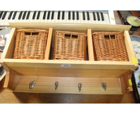 A wall shelf fitted with hooks and three baskets