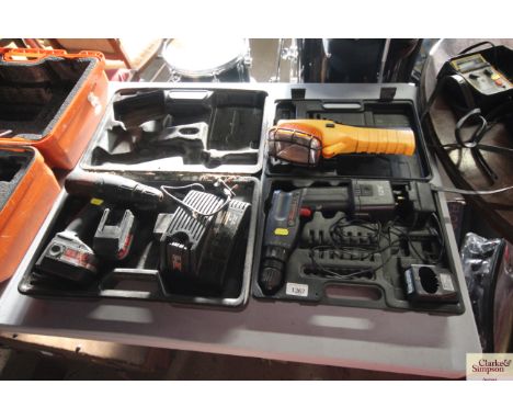 Two cordless drills in cases with chargers and a work light