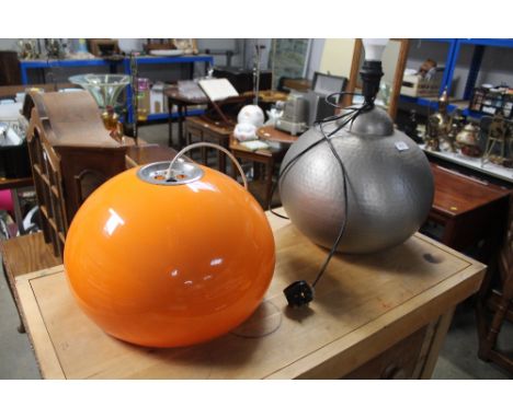 A metal table lamp and orange plastic lightshade