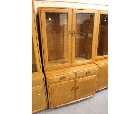 Modern Ercol light elm side cabinet with two bevelled glass doors enclosing shelves above two drawers and two cupboard doors,