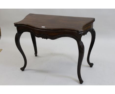 Antique mahogany serpentine shaped card table, the moulded fold-over top having baize lined interior with shaped carved friez