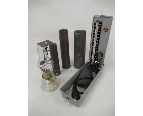 Three World War I brass shell cases, pair of metal postal scales, oil lamp and cased blood pressure meter in original metal c