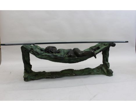 20th Century patinated bronze coffee table in the form of a child in a hammock with glass top, Limited No. 22 of 99, 18ins hi