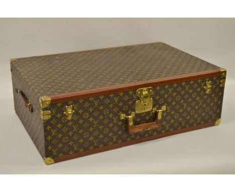 Vintage Louis Vuitton suitcase with brass catches and corner mounts, the hinged lid enclosing a void interior, with original 