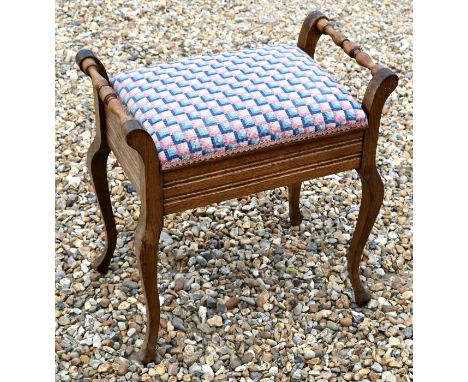 A vintage walnut piano stool with overstuffed hinged seat enclosing a storage well