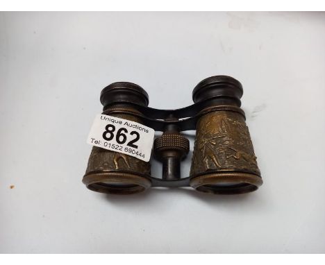 A pair of vintage opera glasses with relief brass hunting scenes
