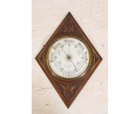 Early 20th Century Aneroid Barometer having a white enamelled dial set within a carved oak diamond shape wall mount. 