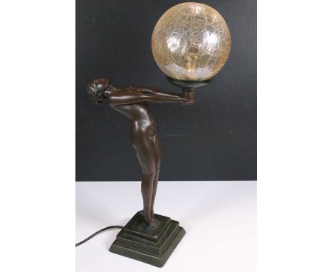 Art Deco style lamp base featuring a stylised lady holding a bowl, raised on a square stepped base, with globular glass shade