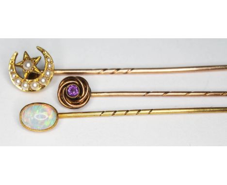 A group of three stick pins comprising one 9ct gold set with an amethyst coloured stone, one 15ct gold set with an opal and o