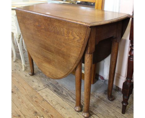 An oval oak gate leg table, standing on pad feet