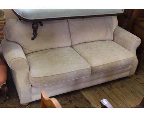 A modern two seater cream upholstered sofa