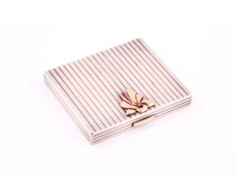 A French Art Deco Cartier style compact; of rectangular ribbed form, with applied gold and ruby stylised ribbon decoration to