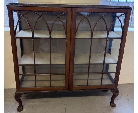 A vintage dark wood 2 door glass display cabinet raised on 4 ball &amp; claw footed legs. Fabric lined interior with 2 fabric