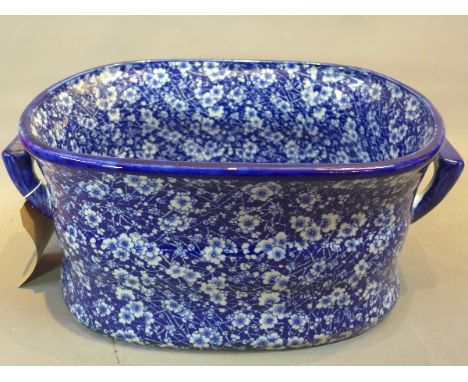 A blue and white ceramic foot bath with floral decoration.
