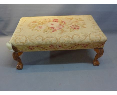 A large Georgian style foot stool with embroided tapestry upholstery, raised on paw feet. 