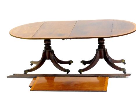 An early 20thC Georgian style mahogany and satinwood cross banded twin pedestal dining table, with two additional leaves, rai