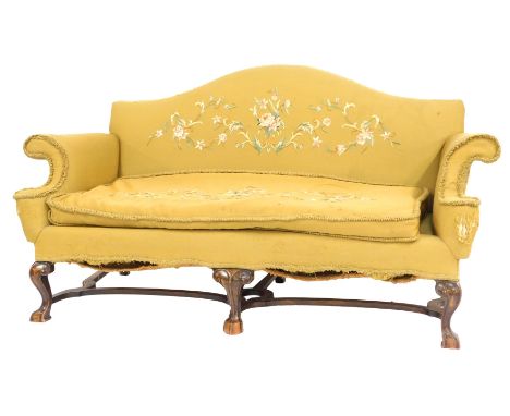 A George II style mahogany framed camel back sofa, with hand floral embroidered yellow fabric, raised on short cabriole legs,