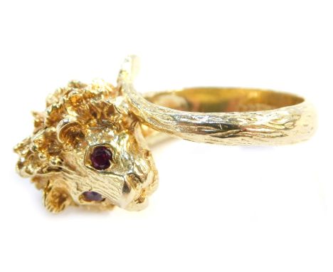 A 9ct gold dress ring, in the form of a cast lion's head with ruby eyes, the shank formed by a tail, size R 1/2, 15.3g all in