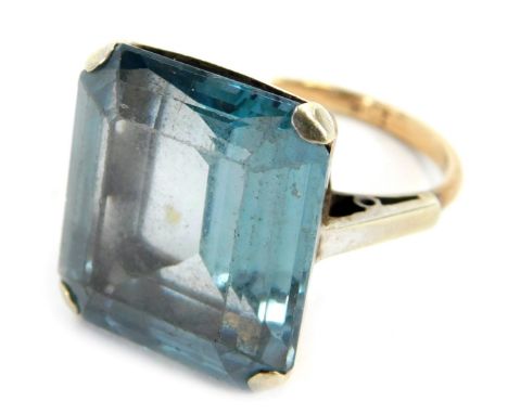 An aquamarine ring, the faceted rectangular cut stone in a high claw basket setting, in a yellow metal mount stamped 9ct, 8.5