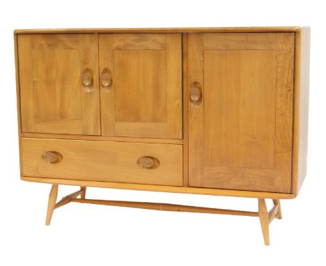 An Ercol light elm sideboard, with a pair of doors opening to reveal a single shelf, over a frieze drawer, to the right a fur