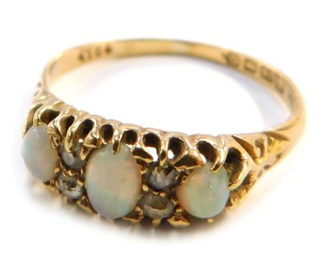 An 18ct gold opal and diamond dress ring, set with three oval opals interspersed by tiny diamonds, Birmingham 1938, size S 1/