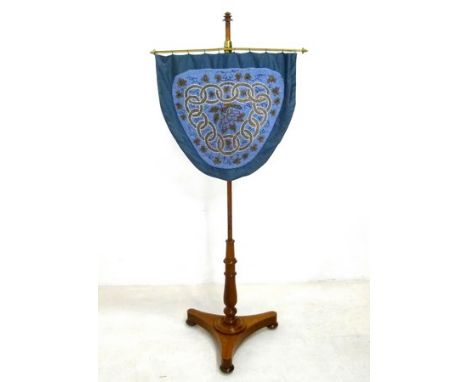 A Victorian oak and brass pole fire screen, with glass beadwork shield shaped banner, the panel 53 by 49cm and 138cm high.