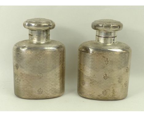 A pair of silver perfume bottles, with hinged lids, reserve monogrammed, engine turned decoration and engraved with fleur de 