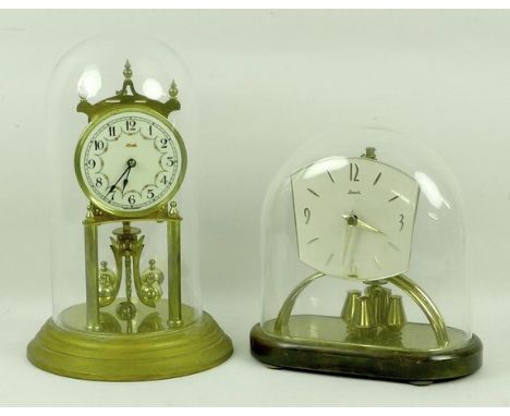 A Kundo Heirloom clock with a glass dome, 30cm, together with a Prescott glass domed mantle clock, 22cm. (2)