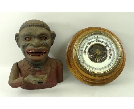 A painted cast iron money box, 'Jolly Nigger Bank' verso, 16cm, and an oak circular cased barometer. 