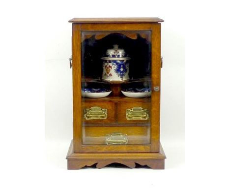 A Victorian oak smoker's cabinet with twin brass carrying handles, the bevelled glass door opening to reveal a shelf with pot