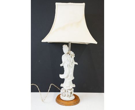 Chinese blanc de chine table lamp in the form of a female deity, with shade, raised on a circular wooden base. Overall height