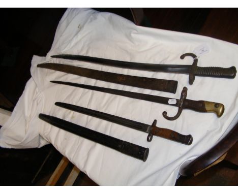 A WWII sword bayonet with scabbard, together with two others (one lacking scabbard)