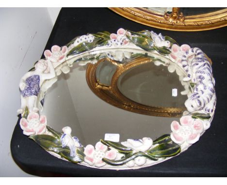 A decorative oval ceramic wall mirror - 58cm wide with tiger and bird relief work