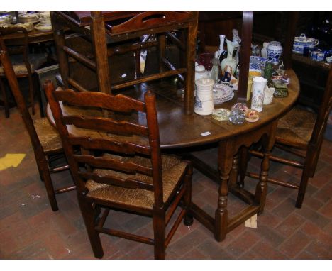 An oak drop leaf oval dining table together with four ladder back chairs