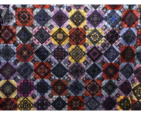 A Modern Patchwork Quilt comprising coloured squares incorporating silk ties, overstitched with gilt thread, with a blue cott