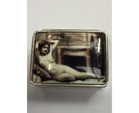 A SILVER PILL BOX WITH AN ENAMEL EROTIC DESIGN ON THE LID 