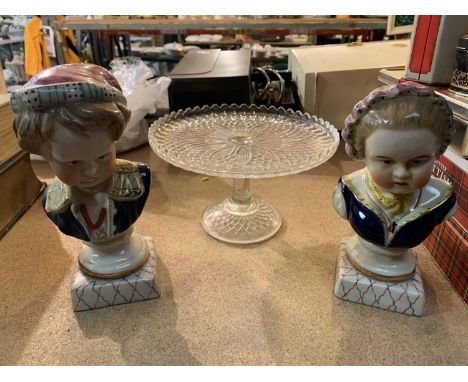 A PAIR OF CERAMIC BUSTS OF CHILDREN AND A GLASS CAKE STAND 