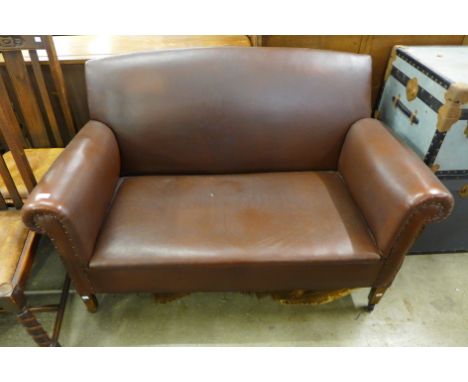 An Art Deco brown leather drop arm settee 