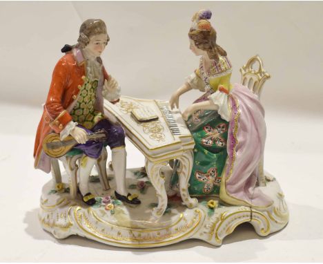 Continental porcelain group of a lady and gentleman, the lady playing the piano, on a scroll gilt base, 22cm long