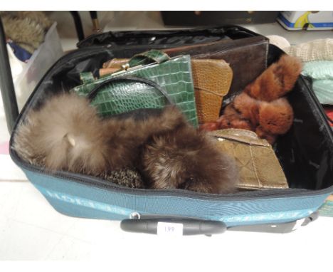 A small suitcase containing a selection of vintage lady's handbags including snakeskin and two fur collars