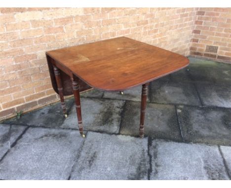 A VICTORIAN MAHOGANY DROP-LEAF TABLE  on ring turned supports with brass casters